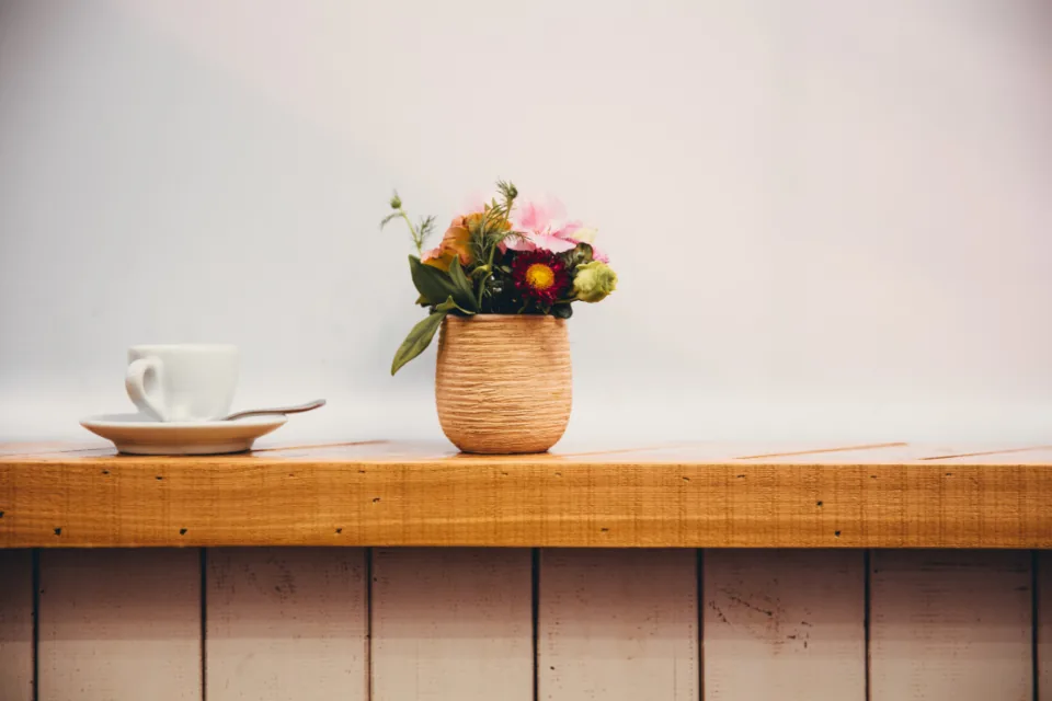 Fresh flowers and a coffee cup on a wooden shelf