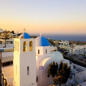 White chapel with a blue dome at sunrise by the sea