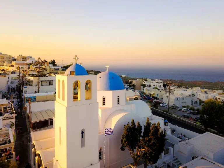 White chapel with a blue dome at sunrise by the sea